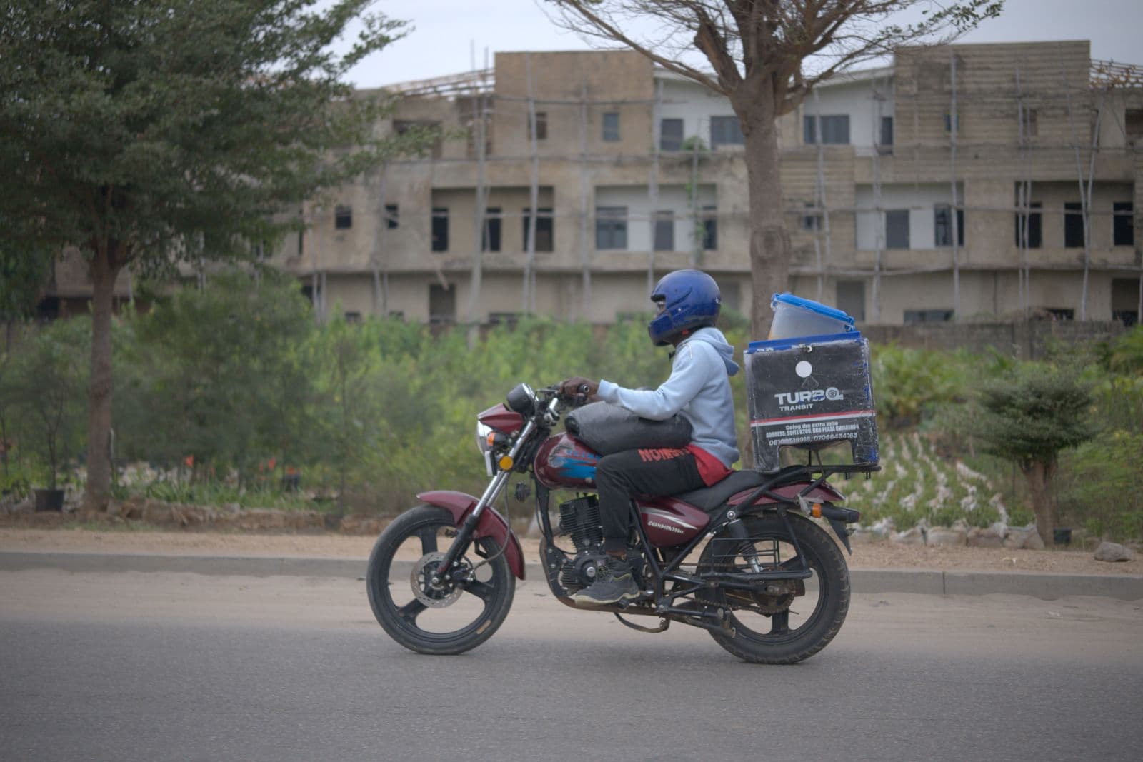 A dispatch rider carrying a delivery box on a Nigerian street